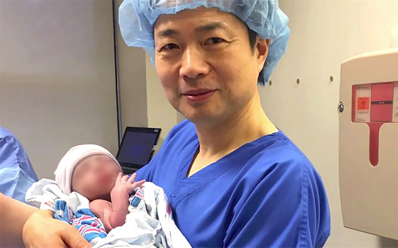 John Zhang sostiene al bebé en el momento de su nacimiento