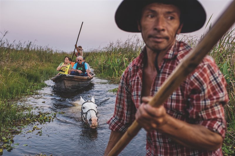 Seguido por la montura sobre la que más tarde cabalgará hasta su casa, Mingo Ávalos impulsa su canoa por un canal mientras otro guía y él dan un tour a unos turistas de visita en el Iberá. Todos ganan con el turismo: los antiguos cazadores y los que trabajan en la ganadería, como Ávalos, encuentran empleos respetuosos con el medio ambiente.