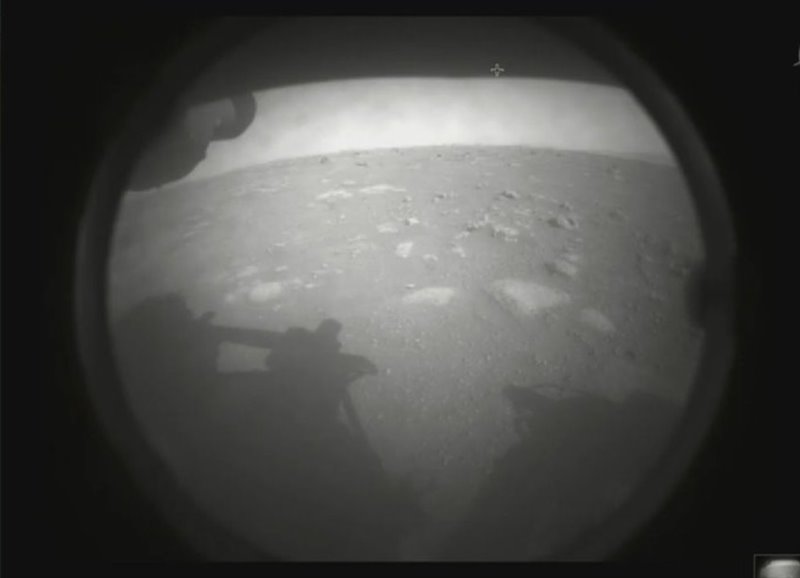 Esta es la primera imagen que envió el rover Perseverance de la NASA después de aterrizar en Marte. La imagen, tomada por una de las cámaras del dispositivo, está parcialmente oscurecida por una cubierta de polvo, aunque puede apreciarse parte de la superficie del lugar de aterrizaje.