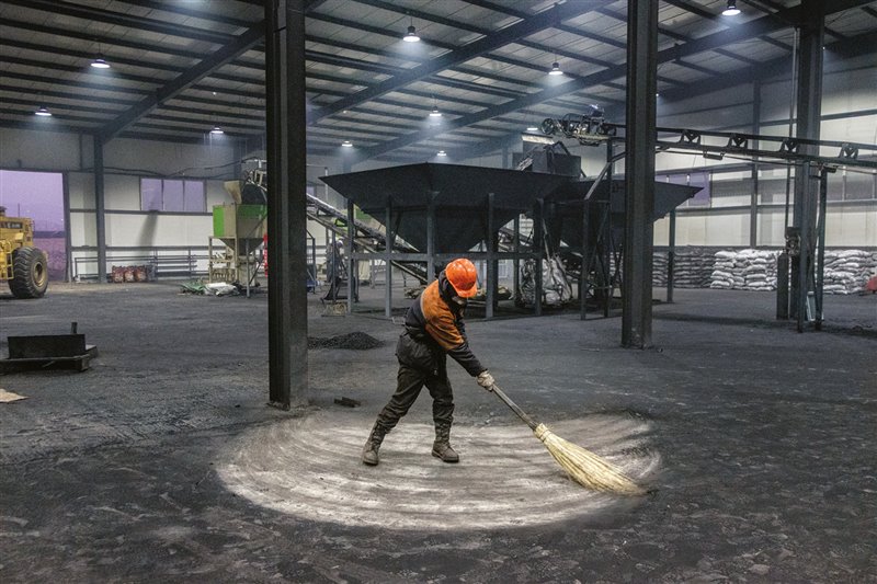 Un hombre pasa la escoba en una planta de procesado donde  el carbón en bruto se transforma en briquetas para su uso en estufas y cocinas domésticas.