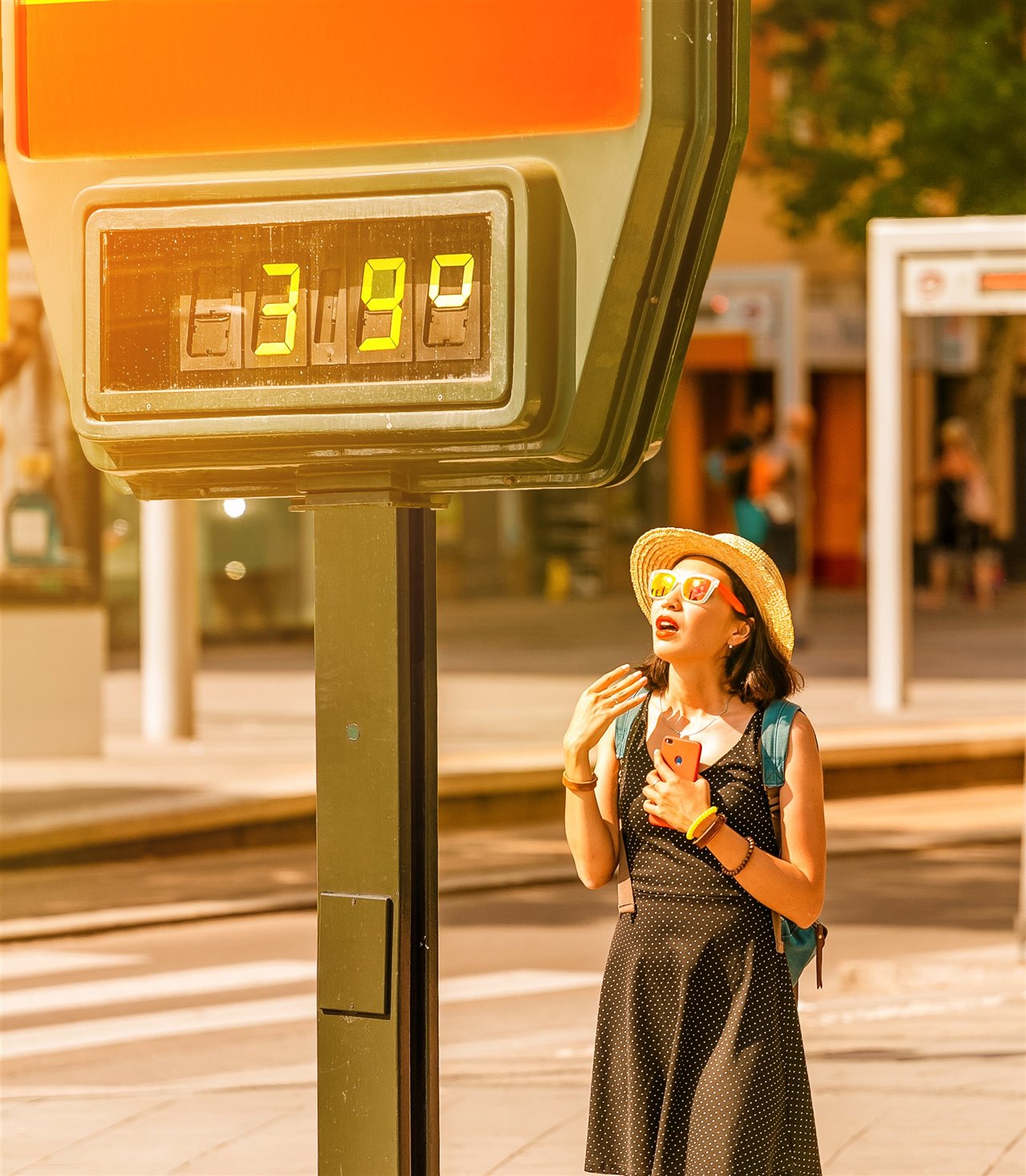 Una mujer acalorada se abanica junto a un termómetro callejero que marca 39 ºC.