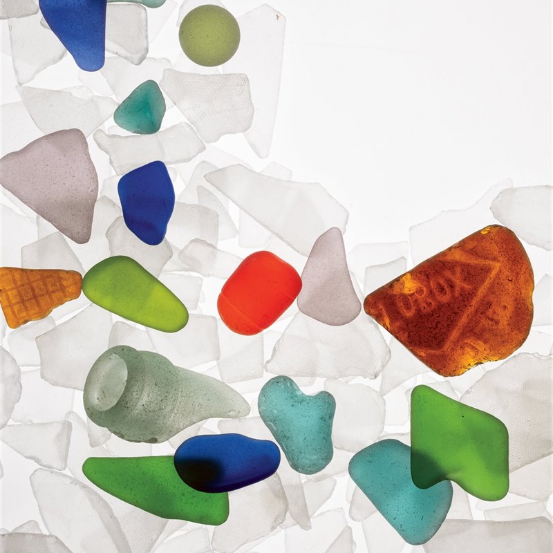 Fragmentos blancos fabricados a partir de vidrios rotos y pulidos que contrastan con los coloridos fragmentos de vidrio marino auténtico.