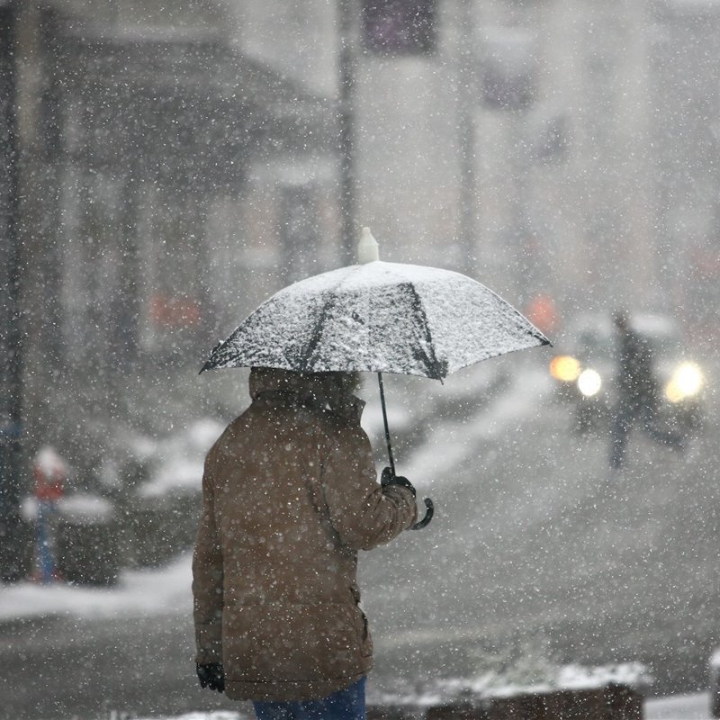 Hombre con paraguas durante una tormenta de nieve 