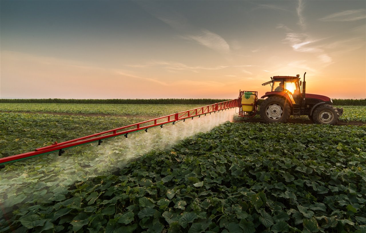Tractor pulverizando pesticidas en el campo de soja.