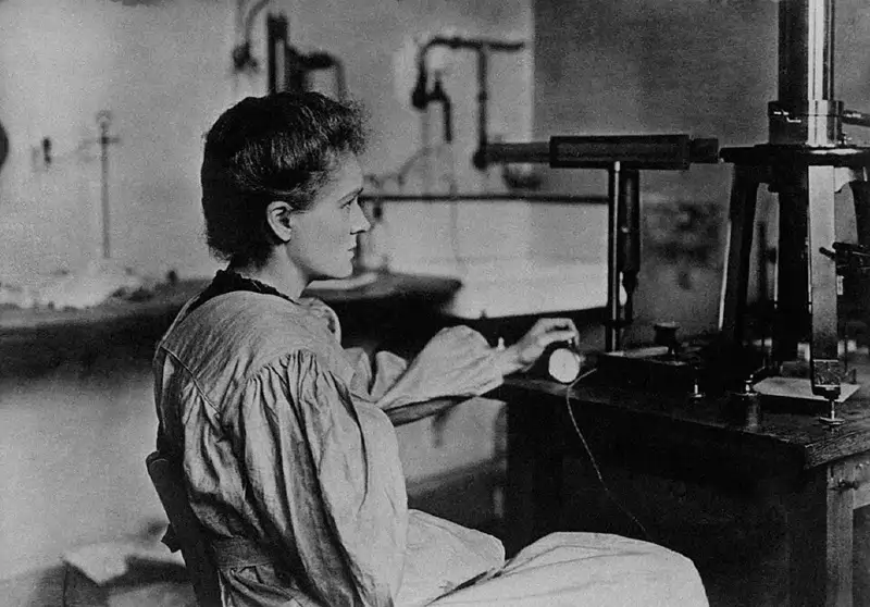 Marie Curie trabajando en su laboratorio hacia 1900 con instrumental destinado a medir las débiles corrientes eléctricas producidas por sustancias radiactivas.