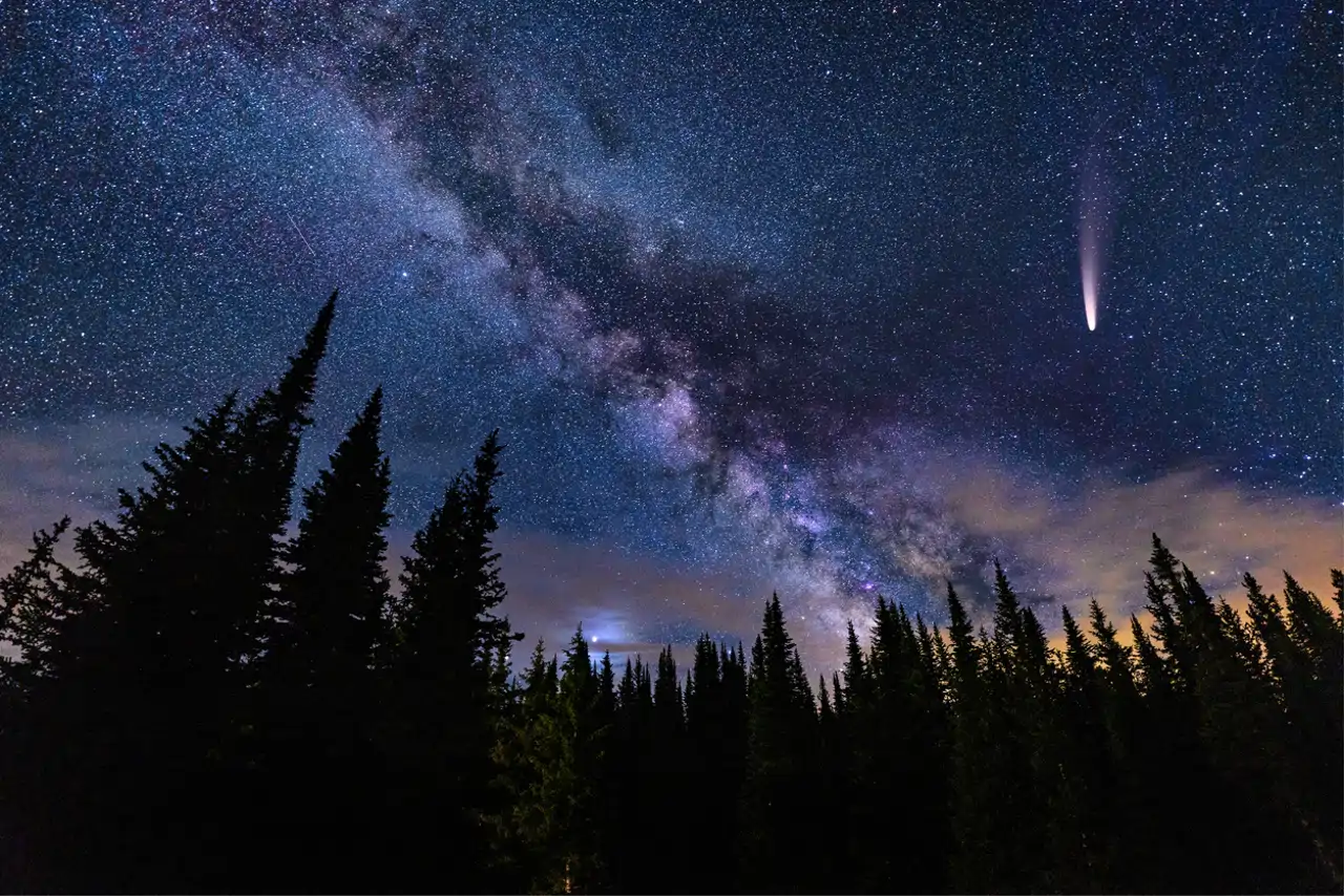 Un cometa sobrevolando con la vía Láctea de fondo
